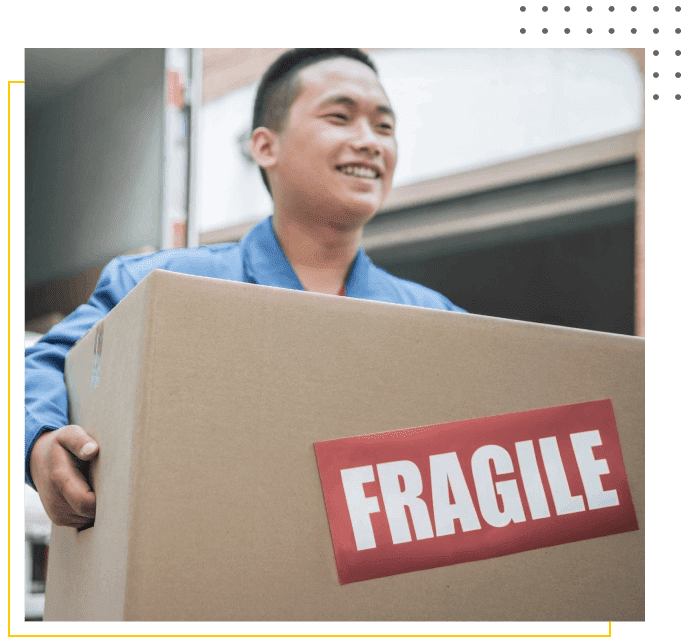 Person smiling while carrying a cardboard box labeled "FRAGILE.